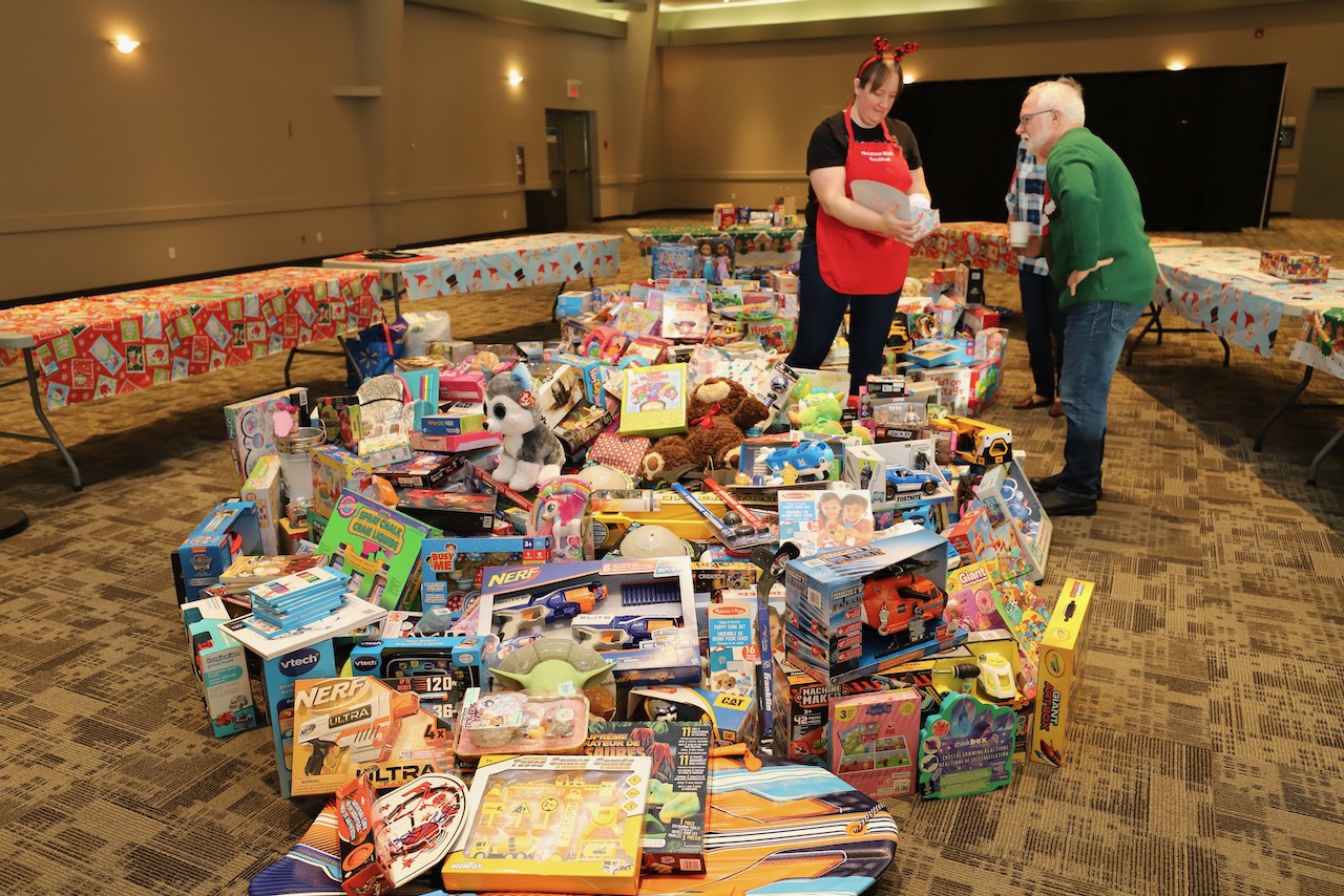 Two volunteers organizing a large pile of donated Christmas toys