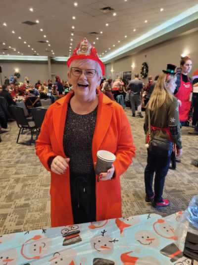 A smiling guest in a red coat wearing a Christmas crown at the breakfast