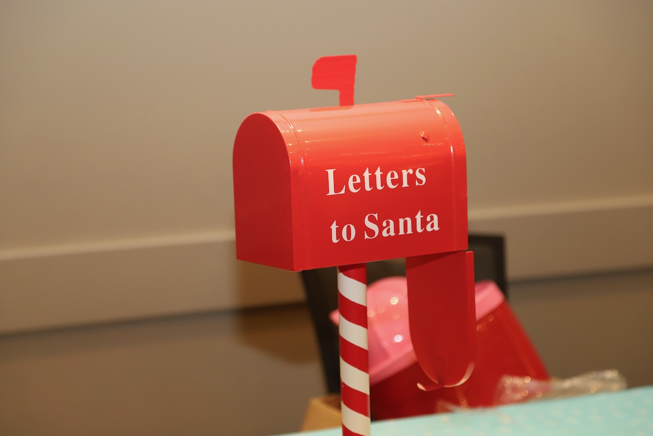 Red 'Letters to Santa' mailbox on a candy-cane striped post at the event