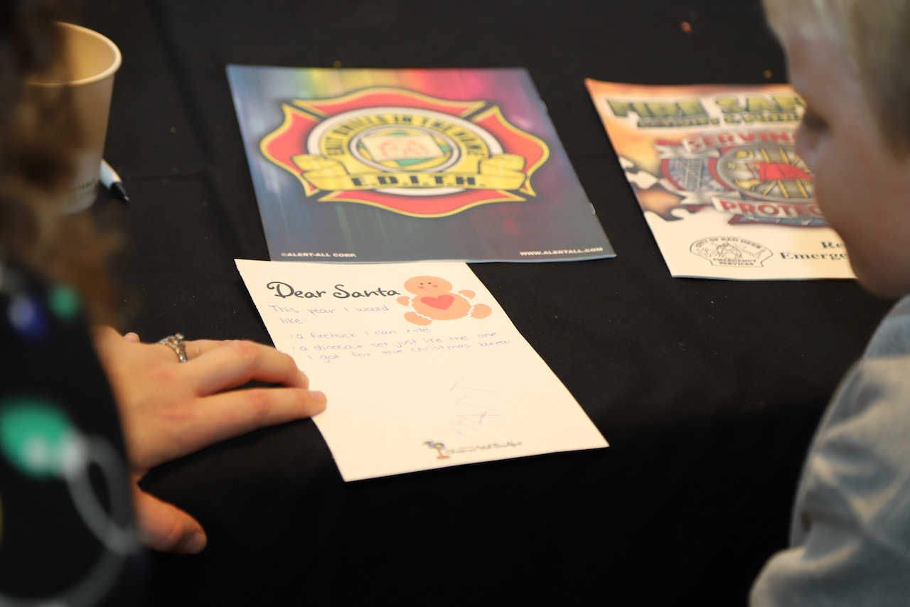 A child at the event writing a letter to Santa with a volunteer